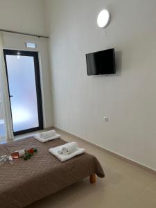 a room with a bed with towels and a flat screen tv at Sun's Suites in Asprovalta