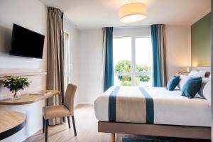 a hotel room with a bed and a desk and a window at Residhome Chartres in Chartres