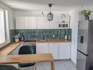 uma cozinha com armários brancos e uma mesa de madeira em Appartement 3 pièces avec parking couvert gratuit. em Le Pré-Saint-Gervais