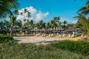 a beach at a resort with chairs and palm trees at Iberostar Waves Bahia - All Inclusive in Praia do Forte