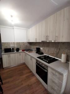 - une cuisine avec des placards blancs et une cuisinière dans l'établissement Apartament Jenny, à Mangalia