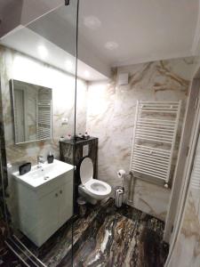 La salle de bains est pourvue de toilettes blanches et d'un lavabo. dans l'établissement Apartament Jenny, à Mangalia