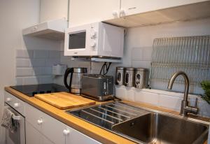 a kitchen counter with a sink and a microwave at 121 Studio - Central Studio Apartment, Terrace & Full Kitchen - Airport & Train Shuttle in Bishops Stortford