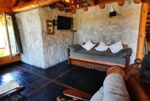 a living room with a couch in a stone wall at Neli Maria in Villa Pehuenia