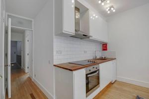 uma cozinha com armários brancos e piso em madeira em Flat C, Old Street em Londres