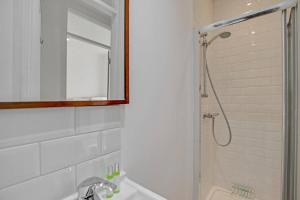 La salle de bains est pourvue d'une douche, d'un lavabo et d'un miroir. dans l'établissement Flat C, Old Street, à Londres