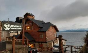 una casa in legno con un cartello di fronte all'acqua di Hostería Nórdico Lake by Nordic a San Carlos de Bariloche