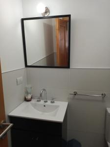La salle de bains est pourvue d'un lavabo blanc et d'un miroir. dans l'établissement Departamento luminoso PB, à San Martín de los Andes