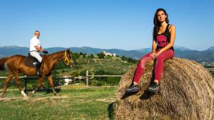 uma mulher sentada num fardo de feno com um homem a cavalo em Agriturismo Rivoli em Spoleto