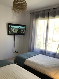 a bedroom with two beds and a tv on the wall at Albatros Golf View 2394 in Casares