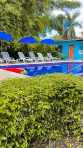 a swimming pool with blue umbrellas and chairs next to at Mar e Lua Flats - Maresias in Maresias