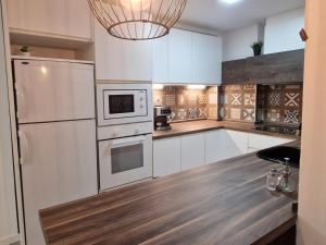 a kitchen with white cabinets and a chandelier at Selena Beach in Cullera