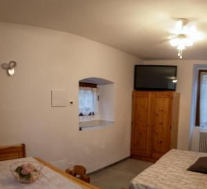 Residenza Cotruta Spiazzo في سبياتزو: غرفة نوم مع تلفزيون بشاشة مسطحة على الحائط
