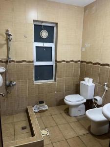 uma casa de banho com um WC, um lavatório e uma janela em Shihan hotel suites em Amã