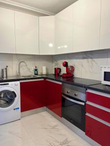 una cucina con armadi rossi e bianchi e una lavatrice di Elegant style 3-bedroom brand new apartment a San Miguel de Abona