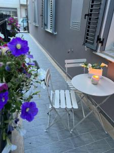 une table et des chaises sur une terrasse avec des fleurs violettes dans l'établissement Appartamento Melissa, à Porto SantʼElpidio