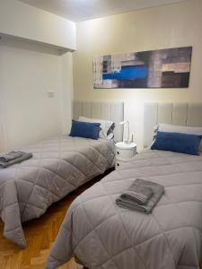 2 camas en una habitación blanca con almohadas azules en Departamento Fabuloso 4 en Rosario