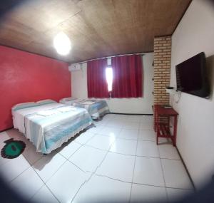 a room with two beds and a flat screen tv at Pousada Sena in Flecheiras
