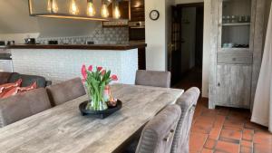 un tavolo in legno con sedie e un vaso di fiori sopra di De Burkelhoeve app.A a Maldegem