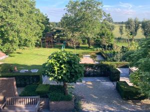 un jardín con un parque con un banco y árboles en De Burkelhoeve app.A, en Maldegem