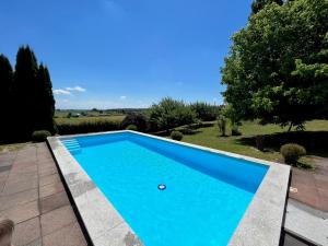 une piscine bleue dans une cour arborée dans l'établissement Traumhaftes Poolhaus am idyllischen Ortsrand, à Blaubeuren