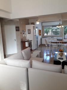 a living room with a white couch and a kitchen at CASA DEL NARANJO in Rosario