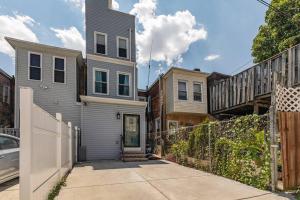 a house with a fence next to a driveway at Trendy Fairmount Gem-5 star Location, Roof Deck, PARKING, GR8 for FAMILIES in Philadelphia