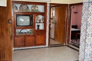 a living room with a tv in a wooden cabinet at Dar Benyounes in Benguerir