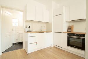 a white kitchen with white cabinets and a sink at Löwe Apartments "Gelb" Tiengen Altstadt in Waldshut-Tiengen