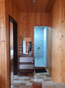 a bathroom with a glass shower in a wooden wall at Apartment Sofia in Batumi