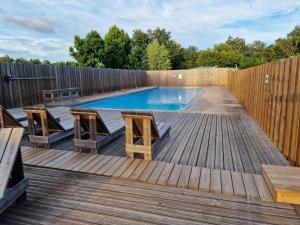 a swimming pool on a wooden deck with a wooden fence at Grand Mobile home dans camping in Mimizan