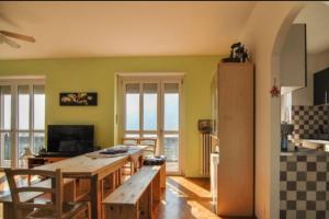 a kitchen with a large wooden table and some windows at TORRE PELLICE Alloggio incantevole con parcheggio privato in Torre Pellice