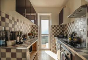 a kitchen with a checkered counter top and a window at TORRE PELLICE Alloggio incantevole con parcheggio privato in Torre Pellice
