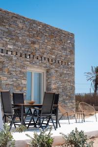 a patio with a table and chairs and a stone wall at CAMPO SUITES in Kampos Paros