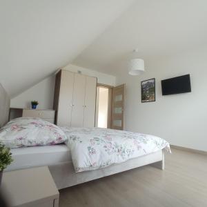 a white bedroom with a bed and a tv at domek u fiedora in Pieniążkowice