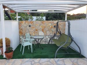 patio ze stołem i krzesłami oraz kamienną ścianą w obiekcie Apartment Elite w Rogoznicy