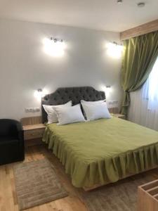 a bedroom with a large green bed with two pillows at NUT HOUSE Retezat in Nucşoara