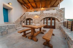 una mesa de madera y bancos en una habitación con una pared de piedra. en Kythera secrets suites, en Viarádhika