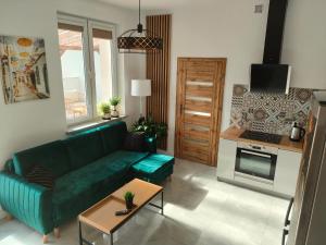 a living room with a green couch and a kitchen at Apartament z widokiem in Mrągowo