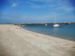 un grupo de personas en una playa con barcos en el agua en Seabreeze Apartment, en Llandrillo-yn-Rhôs