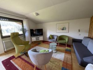 een woonkamer met een bank en stoelen en een tv bij Fewo 1 am Auweg in Hirschegg