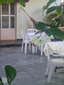 a patio with white chairs and a table and a plant at Hospedaria do Ernesto in Itanhandu