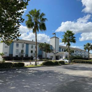 un bâtiment avec des palmiers en face d'une rue dans l'établissement Destiny Palms Hotel Maingate West, à Kissimmee