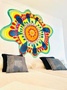 uma grande pintura colorida numa parede acima de uma cama em CASA EL PARAISO em Coín