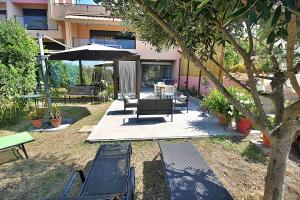 eine Terrasse mit Bänken, einem Tisch und einem Sonnenschirm in der Unterkunft Rez de villa Aspretto Lazaret in Ajaccio