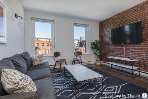 uma sala de estar com um sofá e uma parede de tijolos em 304 Newbury Street by Thatch em Boston