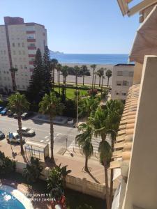 een uitzicht op een parkeerplaats met palmbomen en het strand bij Precioso Atico a pie de playa con piscina. in Motril