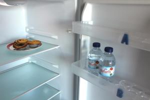 - un réfrigérateur avec 2 bouteilles d'eau et une assiette de beignets dans l'établissement Guesthouse Felicidade, à Lagos