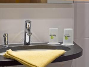 a bathroom sink with two glasses and a yellow towel at Hotel Grüner Baum in Würzburg