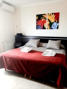 1 dormitorio con 1 cama roja y 2 toallas en SanPier - Alquileres Temporarios en Allen